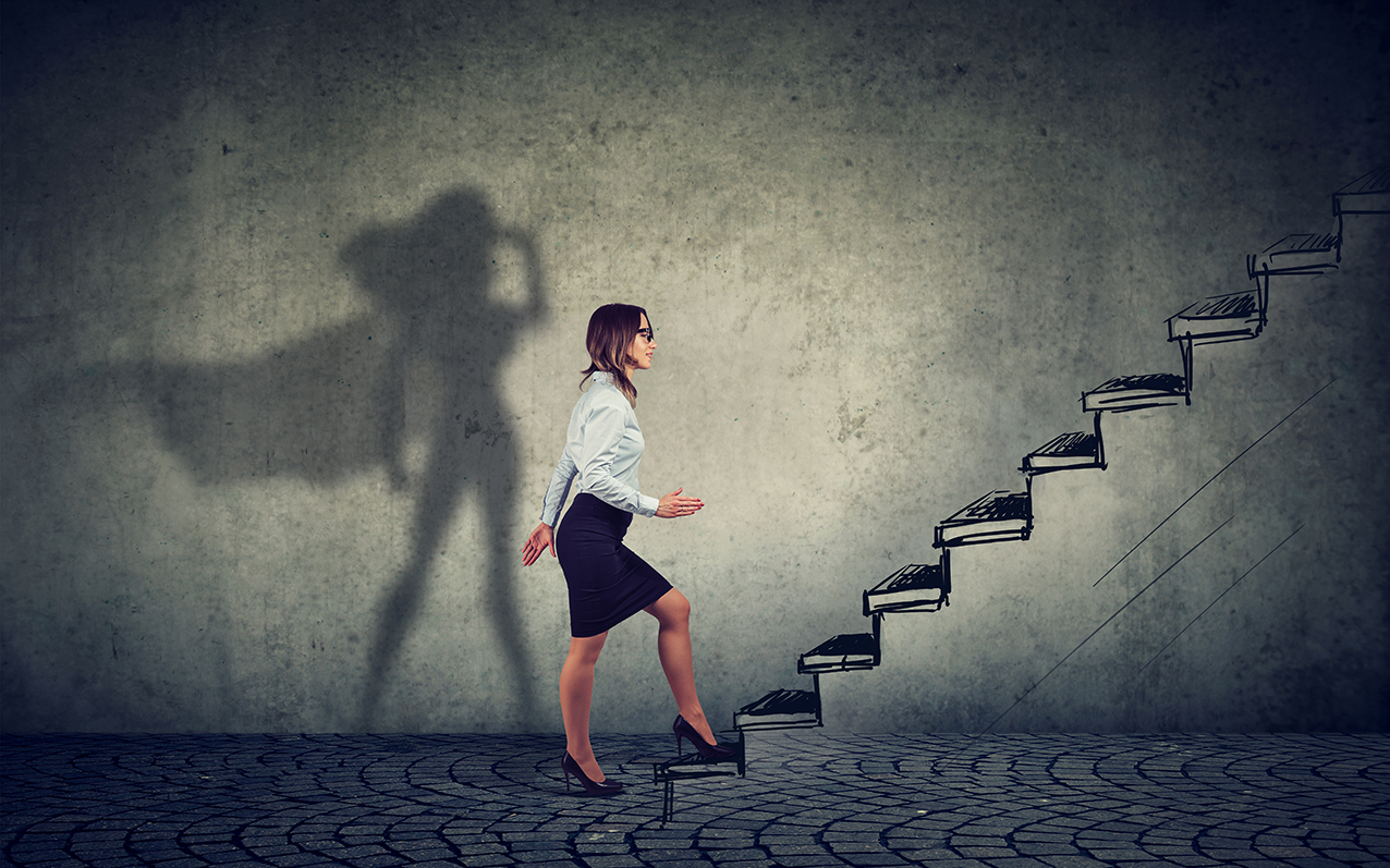 Decorative image of business woman walking up a staircase with her shadow showing a superhero
