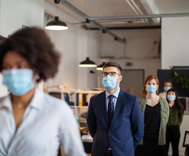 Office workers lined up with surgical masks and safe spacing